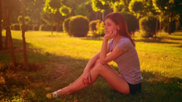 Melancholijna samica siedzi na zielonej trawie — Wideo stockowe