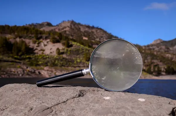 Увеличим стекло Лупы на вулканической скале — стоковое фото