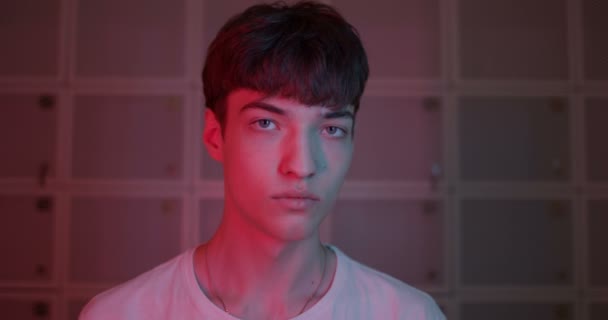 Portret chłodnego Millenial Stylowy facet w białym T-shirt Turning Head i patrząc prosto do kamery stojącej na futurystycznym Neon Pink Lights tle. Zamknij się.. — Wideo stockowe