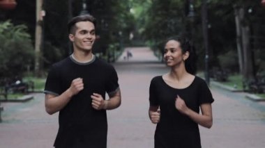 Arkadaşları Genç Adam ve Kadın Heyecanlı ve Rahatlamış Görünüyor Gülümseyen ve Sohbet Eden Koşu Takımları Giyiyor parkta .