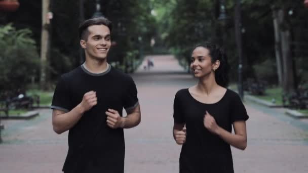 Amis Jeunes hommes et femmes qui ont l'air excités et détendus Sourire et bavarder Porter un jogging Courir dans le parc  . — Video