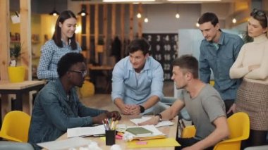 Ofiste bilek güreşi yapan iki genç adam. Neşeli meslektaşlar el çırpıyor, gülüyor ve eğleniyorlar..