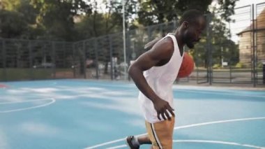Genç Afro-Amerikan Sporcu Basketbol Eğitimi alıyor. Kafkasyalı adam top sürüyor, Şehir Spor Salonu 'nda top atıyor ve sayı yapıyor. Sağlıklı Yaşam Tarzı ve Spor Konsepti.