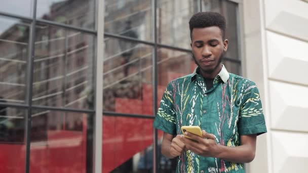 Podekscytowany afrykański facet ze smartfonem. — Wideo stockowe