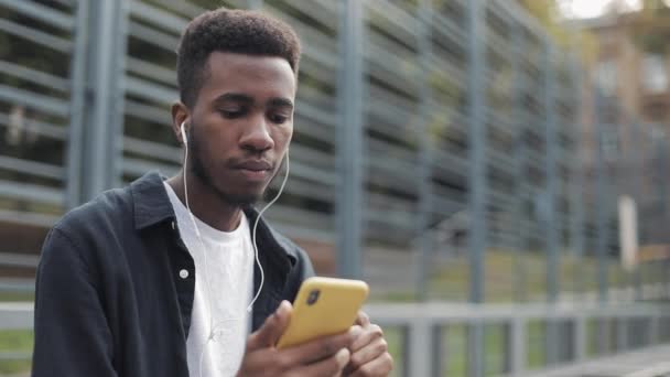 Νεαρός που χρησιμοποιεί το τηλέφωνο και ακούει μουσική. — Αρχείο Βίντεο