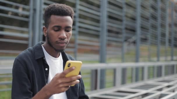 Studente millenario utilizzando il suo smartphone all'aperto . — Video Stock