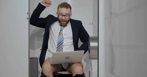 Businessman with notebook sitting in toilet. — Stock Video