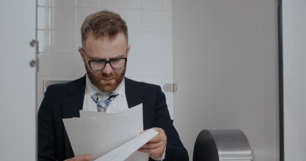 Close up of businessman readind in toilet. — Stock Video