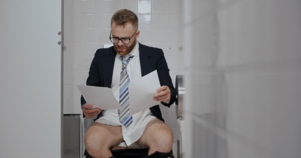 Mann mit Dokumenten in Toilette sieht verwirrt aus — Stockvideo