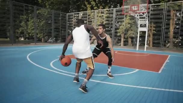 Deux jeunes hommes actifs de race mixte jouant au basket-ball, un contre un sur le terrain de basket-ball sportif de rue, Afro American Man Handling, lancer la balle et marquer. Mode de vie sain et concept sportif . — Video