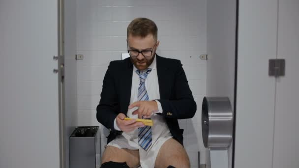 Man in toilet succeding and winning at smartphone. — Stockvideo