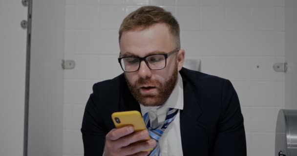Close up de trabalhador masculino estrelando a tela do telefone no banheiro . — Vídeo de Stock