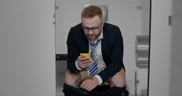 Trabajador masculino con smartphone sentado en cabina wc . — Vídeos de Stock
