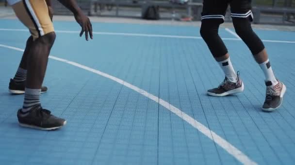 Primo piano di due giovani uomini di razza mista attivi che giocano a basket, rimbalzano e lanciano palla, uno contro uno al campo da basket di sport di strada. Stile di vita sano e concetto di sport . — Video Stock