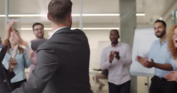 Groupe joyeux de travailleurs multiethniques applaudissant et debout dans la salle de bureau. Les femmes et les hommes employés de bureau rencontrent et saluent quelqu'un qui a l'air heureux, geste bon . — Video