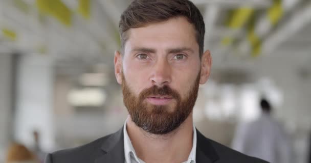 Primer plano de hombre confiado jefe de equipo en traje mirando a la cámara. Retrato de hombre barbudo guapo en los años 30 en el espacio de trabajo de la oficina. Concepto de negocios y personas. Fondo borroso . — Vídeo de stock