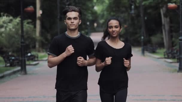 Fiatal kaukázusi férfi és muszlin lány kocogó öltönyben keres nyugodt és boldog futás a parkban koncepció egészséges életmód. — Stock videók