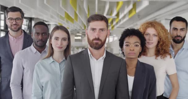 Close-up van gemengde mannelijke en vrouwelijke team van collega 's op zoek naar camera. Groep jonge multi-etnische collega 's die in de werkzone op kantoor staan. Concept van teamwork, carrière, succes business. — Stockvideo