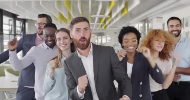 Groupe de heureux collaborateurs d'entreprises multiethniques célébrant contrat réussi. Vue de face de joyeux hommes et femmes de bureau mixtes dansant, se réjouissant et s'amusant ensemble .