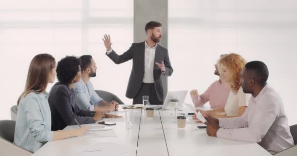 Knappe blanke CEO die nieuwe bedrijfsstrategie presenteert aan zijn collega 's in de vergaderzaal. Man chief in gesprek met groep van diverse medewerkers over de resultaten van het werk op kantoor briefing. — Stockvideo