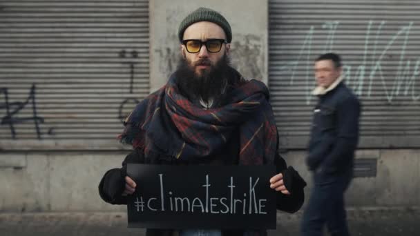 Lviv, Oekraïne - 27 november 2019: Millennial guy protesteert tegen milieuvervuiling. Een ongelukkige man met een klimaatbord. Een man die buiten staat met een plakkaat en naar de camera kijkt. Tijdsverloop. — Stockvideo