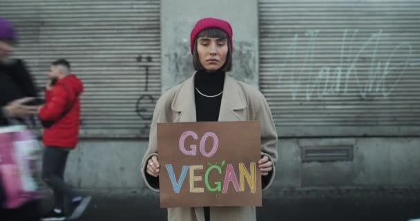 Lviv, Ucrânia - 27 de novembro de 2019: Jovem garota hipster segurando Go Vegan banner sinal e de pé fora. Millennial feminino agitando estilo de vida vegetariano. Desfasamento temporal . — Vídeo de Stock