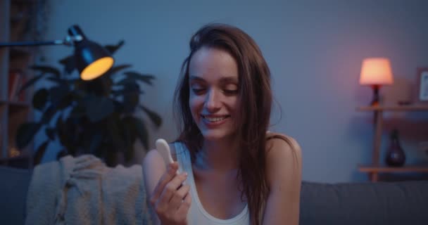 Närbild av flicka som håller ett positivt graviditetstest och gråter på grund av lycka. Ung kvinna ser glad efter att ha fått reda på att hon väntade barn. Begreppet positiva känslor. — Stockvideo