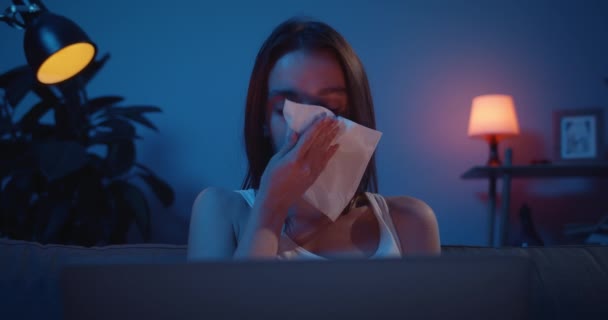 Smutná tisíciletá dívka sotva plakala a používala kapesníky, zatímco se dívala na drama na notebooku. Nešťastná žena v slzách sedí na pohovce s osobním počítačem a stará se o osobní problémy.