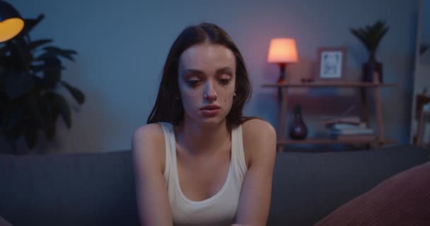 Millennial žena pláče a mytí make-up, zatímco sedí na pohovce doma. Depressed smutný dívka s chaotický řasenka na její tváři znepokojující bolestivý rozešel s přítelem. — Stock video