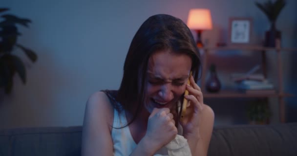 Close up de menina triste chorando e shauting enquanto fala no smartphone. Mulher infeliz não pode acreditar má notícia audição durante o telefonema enquanto sentado no sofá. Conceito de conversa emocional . — Vídeo de Stock