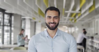 Front view of it trainee looking to camera and smiling at coworking zone. Young startup founder looking happy and standing at office room.Portraits. Concept of work , business, it industry.