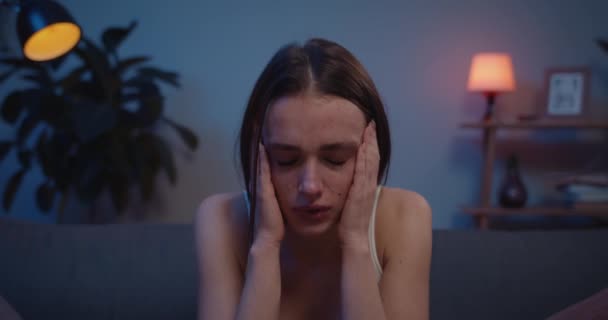 Sluiten van jonge overstuur meisje huilen en houden hoofd met de handen. Verontruste vrouw in depressie zit op de bank met tranen in haar gezicht.Concept van gevoelens en emoties. Achtergrondinformatie. — Stockvideo