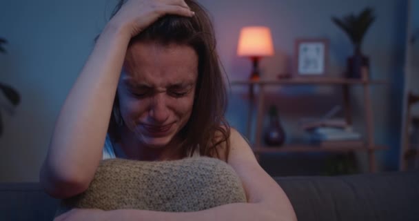 Närbild av olycklig kvinna sitter i fosterställning och gråter. Sorgsen flicka med tårar som rullar nerför kinderna. Begreppet ensamhet och relation. Hem bakgrund. — Stockvideo