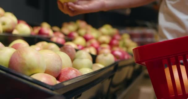 Vista de cerca de las manos del hombre poniendo manzanas en el carrito de la compra. Vista de la cosecha del hombre de pie y tomando frutas mientras que las compras en el mercado de comestibles. Concepto de compras y estilo de vida saludable . — Vídeo de stock