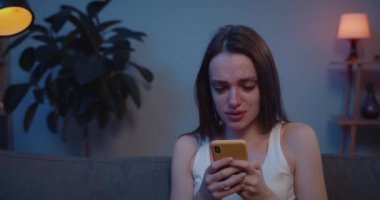 Ayrıldıktan sonra erkek arkadaşıyla fotoğraf çektirirken ağlayan genç bir kızı yakından çek. Kanepede oturan üzgün genç kadın akıllı telefon ekranına bakıyor ve kötü haber aldıktan sonra ağlıyor. .