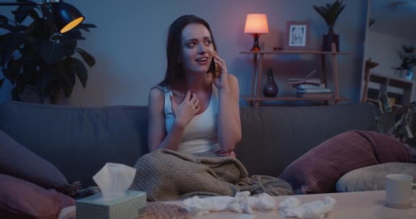 젊은 슬픔에 잠긴 여자가 남자 친구와 의 섹스 후에 전화로 얼굴을 가리고 있습니다. 행복하지 않은 여자가 소파에 앉아서 울고 대화하는 모습. 가정 환경. — 비디오