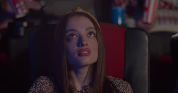 Close-up van jonge vrouw gezicht zitten in stoel en kijken naar interessante film in de bioscoop. Mooi meisje in de bioscoop. Concept van entertainment. — Stockvideo