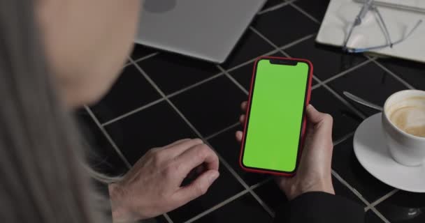 Visão traseira da mulher velha usando smartphone moderno e tela tocante. Feche de mãos de mulheres que pressionam a tela verde de telefone. Conceito de negócio, tecnologia e trabalho . — Vídeo de Stock