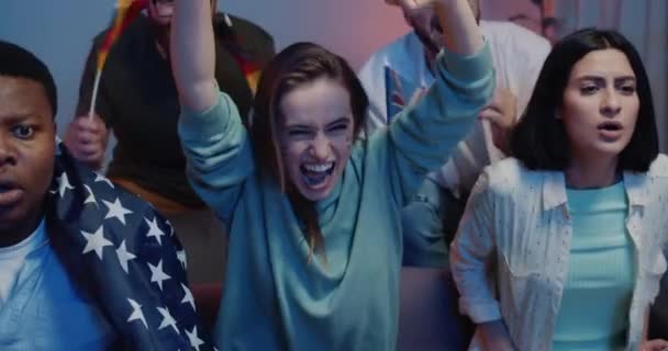 Gros plan de fille excitée avec des drapeaux suédois se réjouissant tout en regardant le sport à la télévision. Focus sur la femme avec des drapeaux souriant tout en étant assis sur le canapé avec des amis contrariés soutenant une autre équipe .