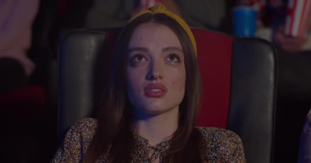 映画館でスリラー映画を見て恐怖の少女のクローズアップ。映画館に座っている間に映画の中で怖い瞬間に千年の女性の顔の反応。芸能の概念. — ストック動画