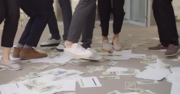 Primer plano de las piernas del equipo de la oficina haciendo un baile divertido en documentos y billetes. Felices trabajadores de oficina regocijándose, bailando sobre papeles y dinero, teniendo fiesta en la oficina . — Vídeos de Stock