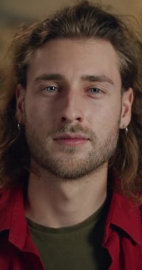 Ciddi bir milenyum adamının başını çevirip kameraya baktığı yakın plan görüntüsü. Yakışıklı erkek heykeltraşın portresi. Dikey video. El yapımı sanat ve insan kavramı..