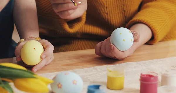 Gros plan des mains de la mère et de la fille colorant les œufs de Pâques avec des couleurs et un pinceau. Œufs de Pâques colorés. Préparation de Pâques Image En Vente