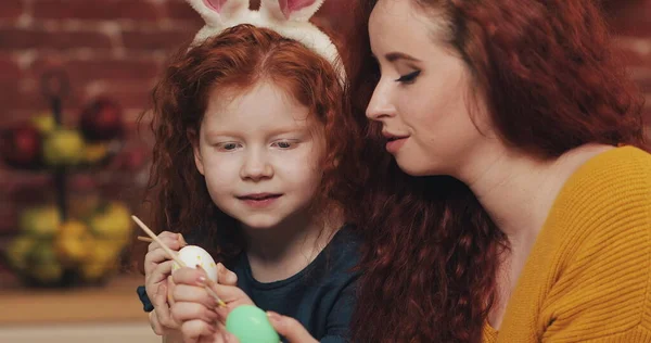 Feliz Páscoa. A mãe e a filha pintam ovos. Família feliz se preparando para a Páscoa. Usam orelhas de coelho. Fotos De Bancos De Imagens Sem Royalties