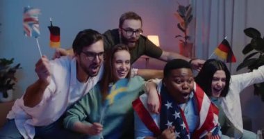 Bayraklı heyecanlı arkadaşlar spor şampiyonasını izlerken birlikte iyi vakit geçiriyorlar. Bir grup genç insan kanepede otururken tezahürat yapıyor, bağırıyor ve sarılıyor..