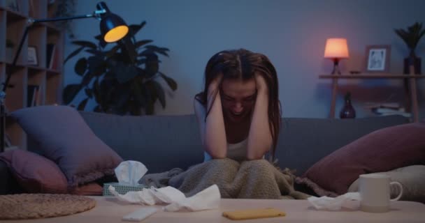 Front view of young woman with broken heart sitting on sofa and crying.Beautiful unhappy girl holding her head and screaming in tears. Concept of: despair, broken love, drama. — Stock Video