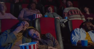 Sinema salonundaki sıkıcı filmler sırasında uyuyan insanların ön görüntüsü. Seyirciler ilginç olmayan filmleri izlerken uykuya dalarlar. Boş zaman ve eğlence anlayışı.