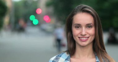 Kameraya bakıp gülümseyen çekici genç bir kadının yakın görüntüsü. Sokakta dikilirken kameraya poz veren bin yıllık güzel bir kızın portresi. Gerçek hayat kavramı.