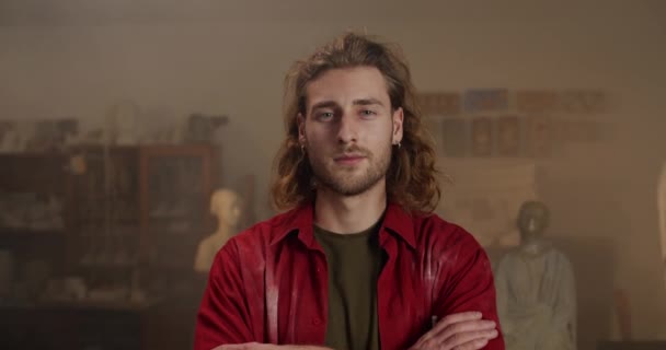 Close up view of handsome young man crossing arms and looking to camera. Confident millennial male sculptor posing while standing in his art studio.Concept of handmade artwork. — Stock Video