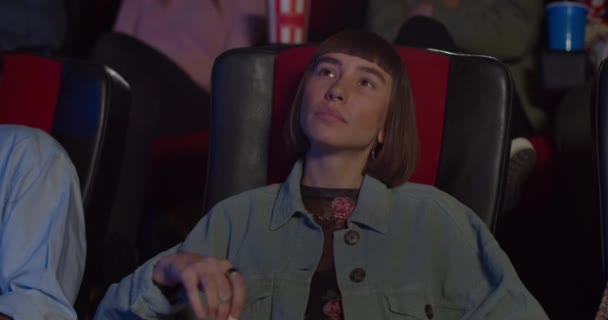 Primer plano de joven hipster cara de chica sentado y viendo interesante película en el cine. Chica con la nariz oreja comer palomitas de maíz y disfrutar de la película en el cine. Concepto de entretenimiento . — Vídeo de stock